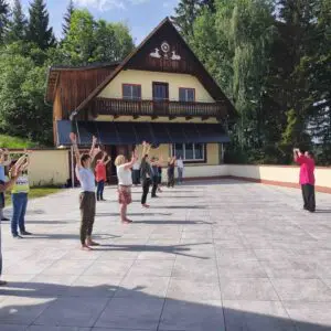 picture of Qigong class with a group of circa 10 people on the main terrace in front of the Kalachakra Temple in Austria